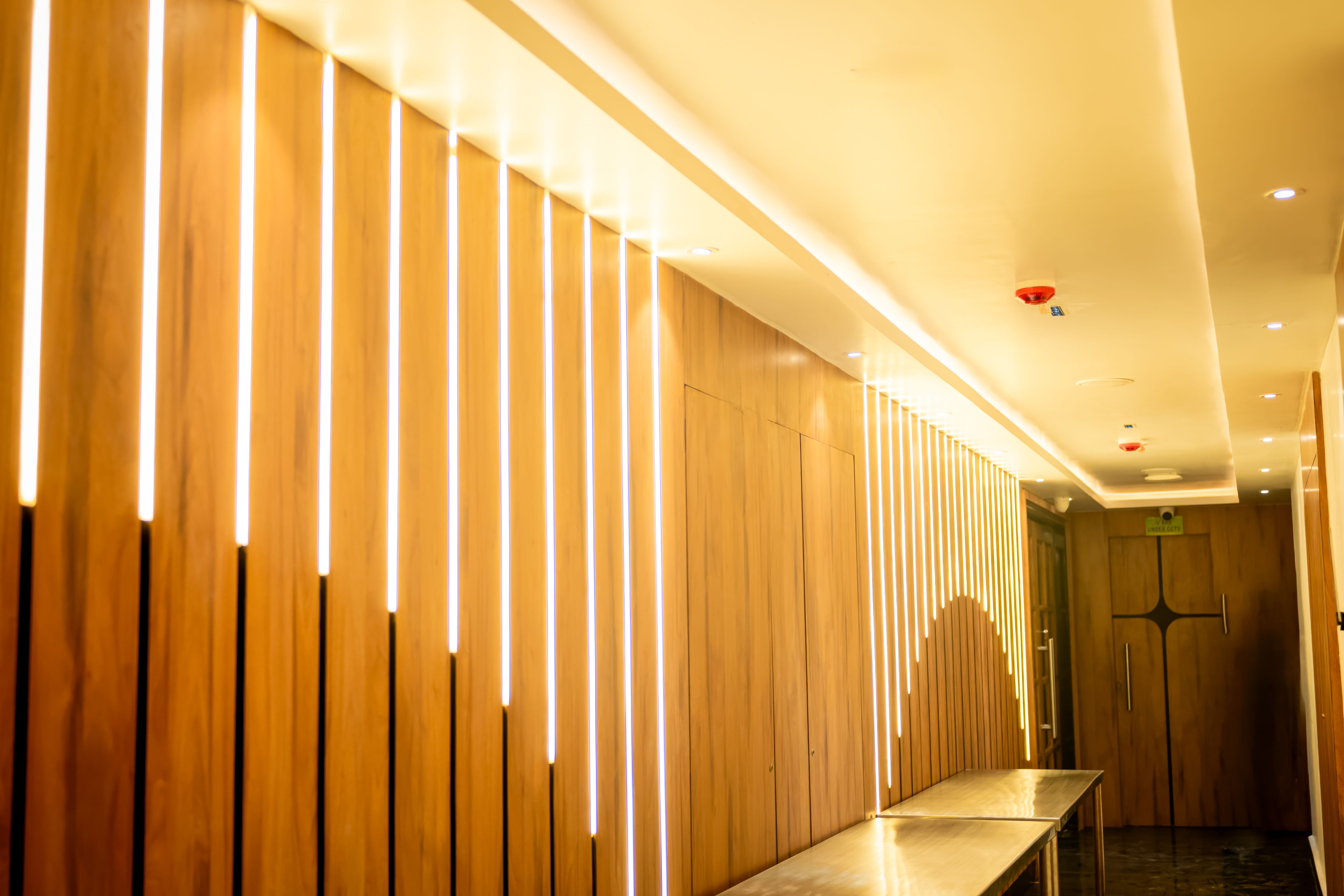 Modern hallway with vertical LED profile lights installed on wood panels